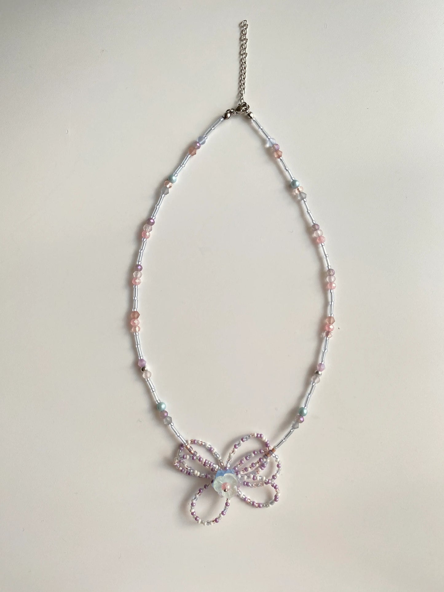 Flat lay of HuibenCraft 1-of-1 long necklace on a white table, showing rhythmic tube and seed bead details.