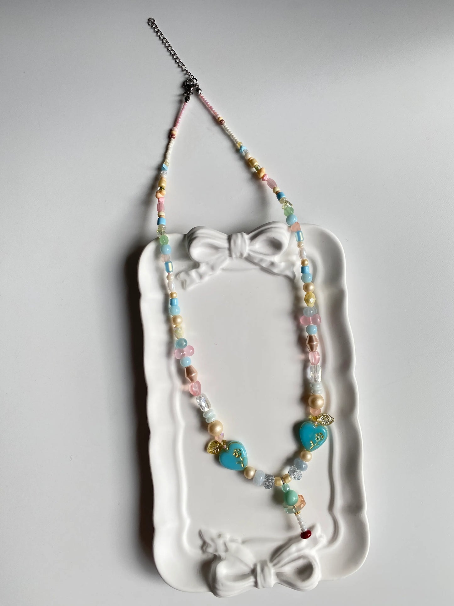 Close-up of a hand-assembled 3D mint ice cream pendant in a ceramic dish, showcasing the mint green pearls.