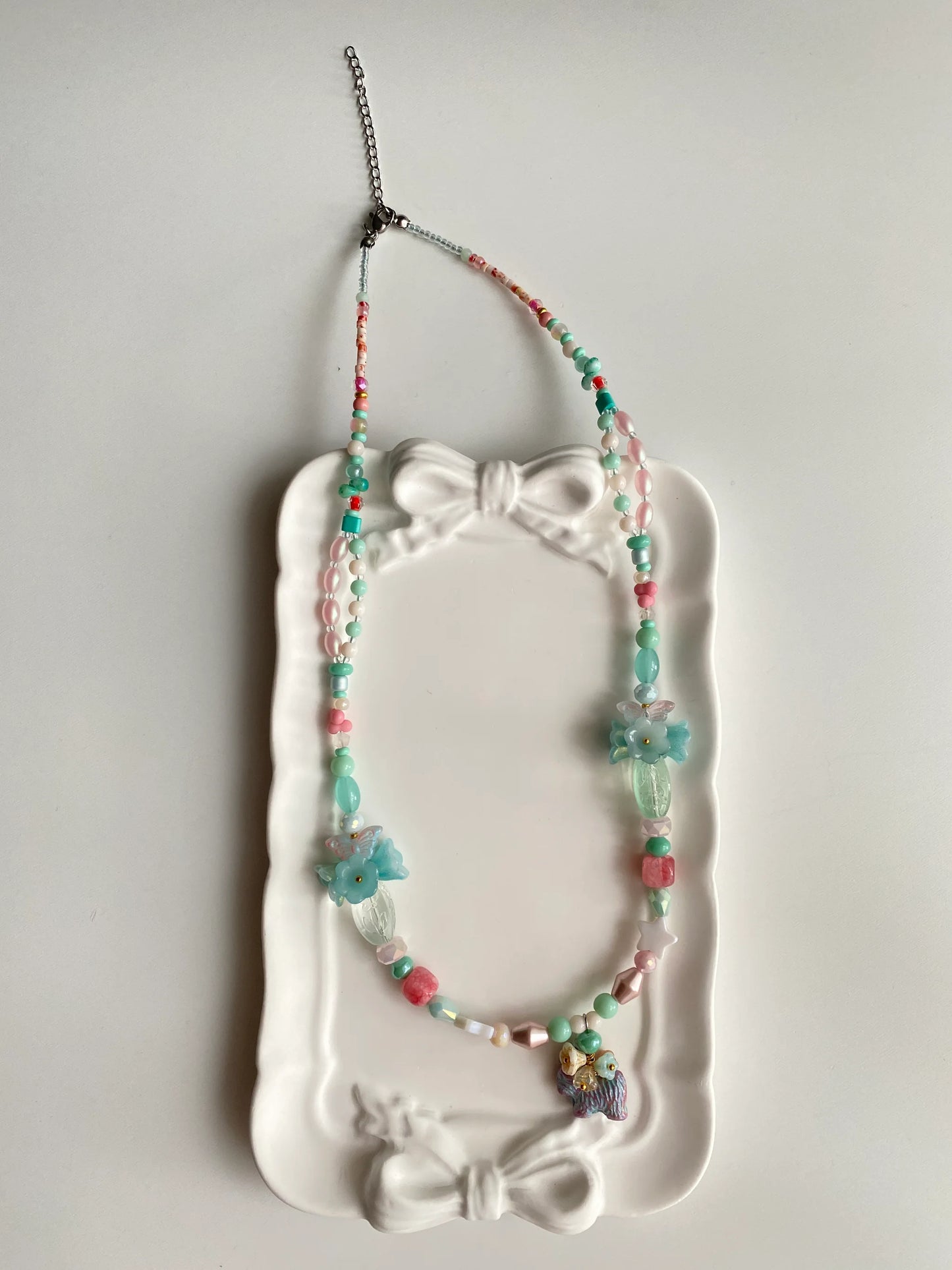 HuibenCraft 1-of-1 charming layered necklace with a blooming flower dog pendant in a white ceramic dish, a whimsical gift for nature lovers.