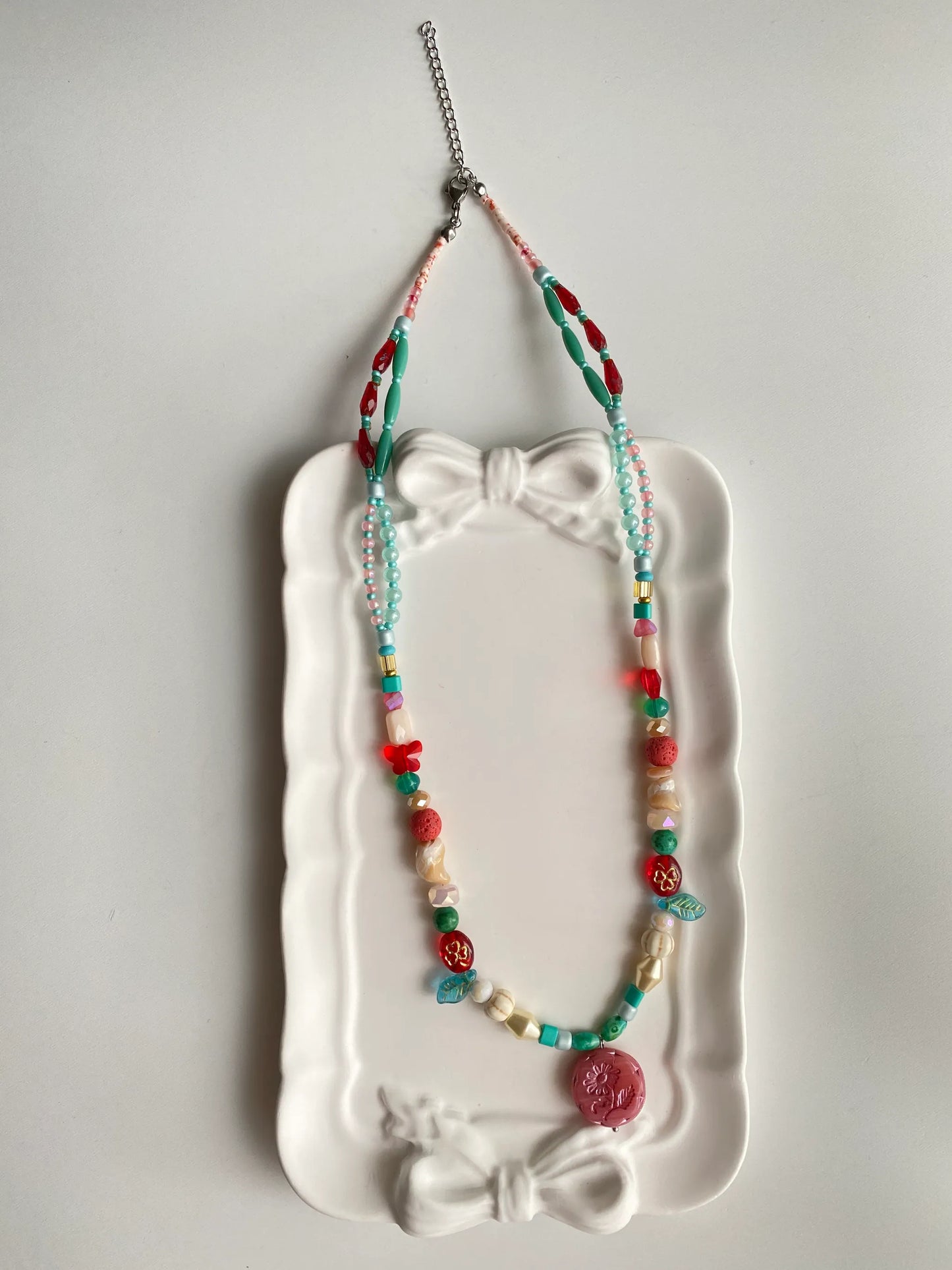 HuibenCraft 1-of-1 dreamy layered necklace with colorful glass and stone beads in a white ceramic dish, inspired by childhood memories.