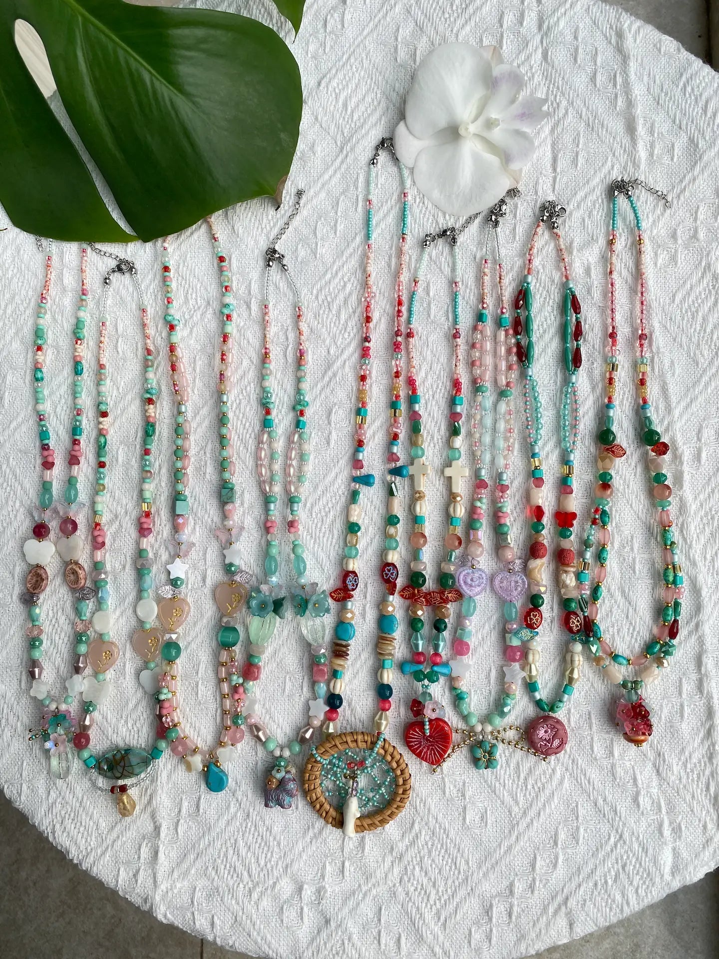 A vibrant flat lay of 10 HuibenCraft 1-of-1 boho-style necklaces featuring rattan dreamcatchers and turquoise stones, styled in natural sunlight.