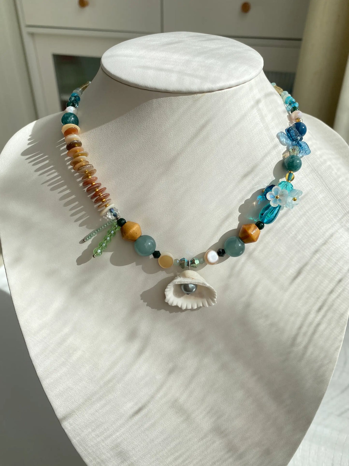Close-up of the HuibenCraft 1-of-1 Deep Blue Sea Shell Necklace worn on a mannequin neck, showing perfect collarbone placement.