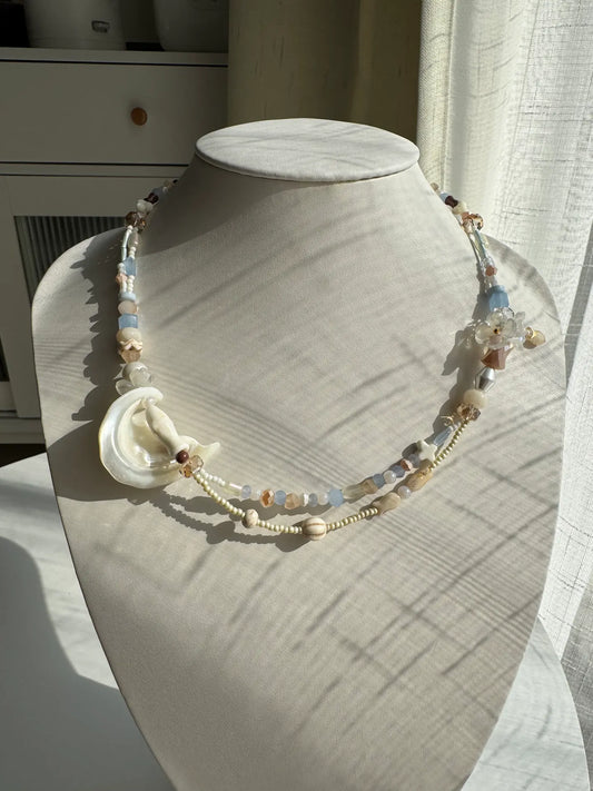 A 1-of-1 boho ocean-inspired layered necklace with a 3D beaded flower bouquet on one side and a white pine fish on the other.