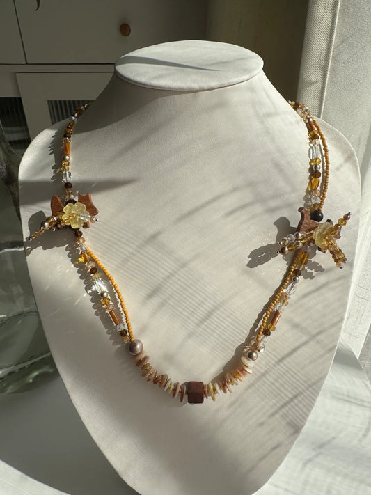 A 1-of-1 double-layered beaded necklace featuring handcrafted cat and dog coconut shell buttons with floral details, displayed on a jewelry bust.