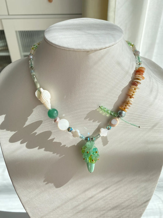 Handcrafted 1-of-1 floral necklace featuring a Czech glass vase pendant and shell accents worn on a mannequin neck.