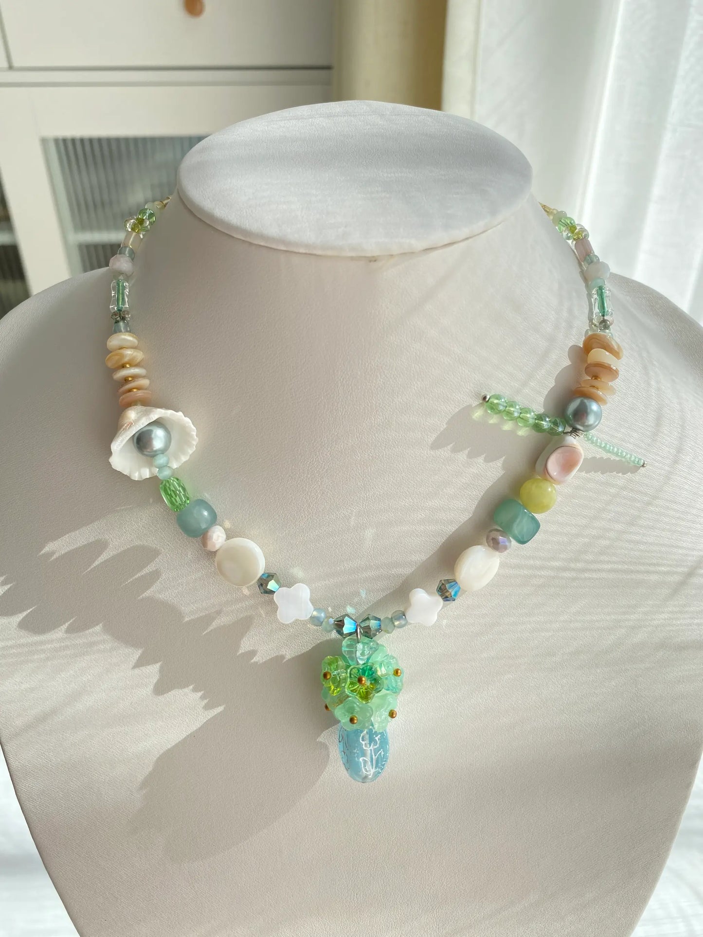 Handcrafted 1-of-1 floral necklace featuring a Czech glass vase pendant and genuine shell accents worn on a mannequin neck.