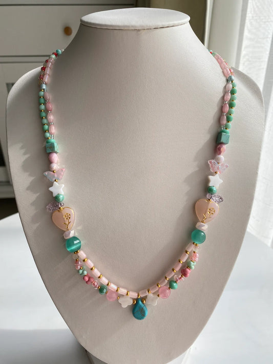 A 1-of-1 long double-layered necklace (59cm) blending ethnic and cute styles with blue, pink, and gold beads on a jewelry bust.