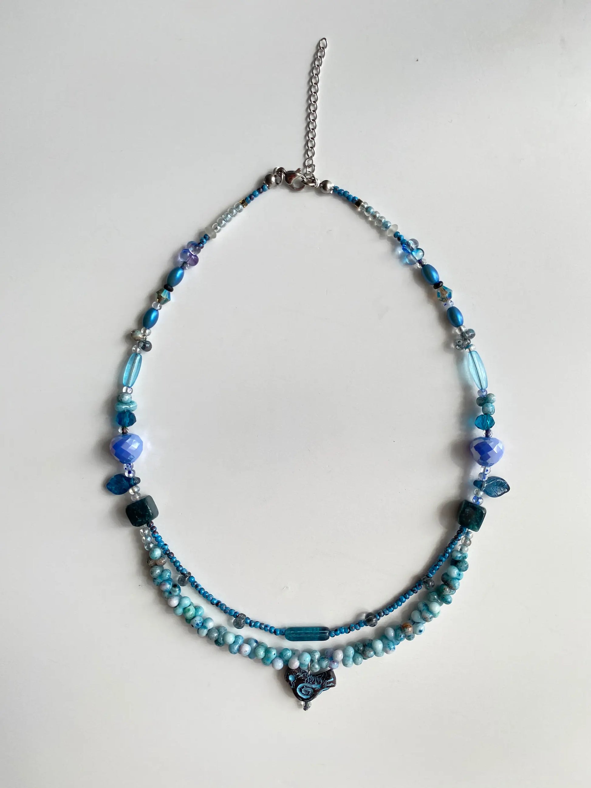 Flat lay of HuibenCraft 1-of-1 necklace on a white table, showing the double-layered structure, chicken pendant, and vintage bead details.
