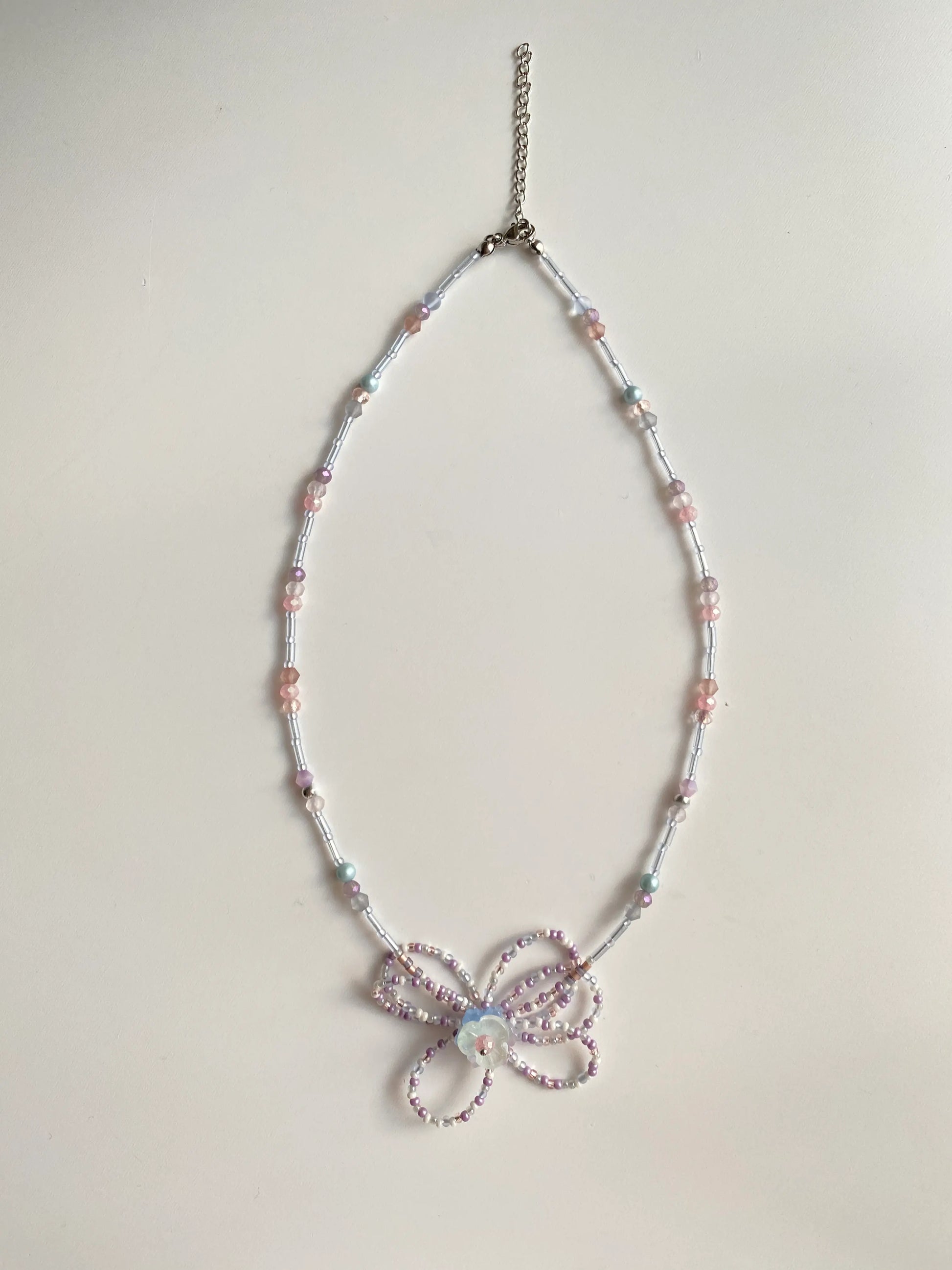 Flat lay of HuibenCraft 1-of-1 long necklace on a white table, showing rhythmic tube and seed bead details.