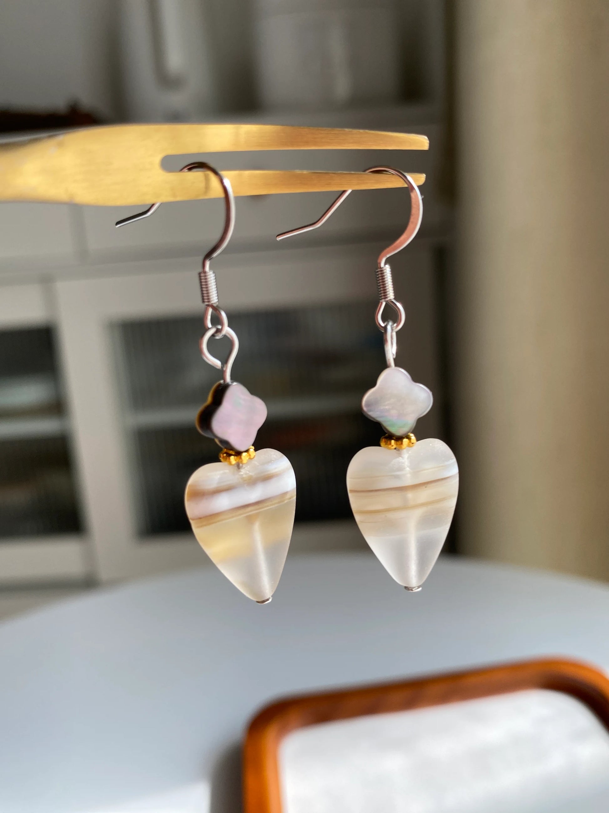 A 1-of-1 pair of minimalist retro earrings featuring frosted heart-shaped Czech glass and black clover shells on a fork.