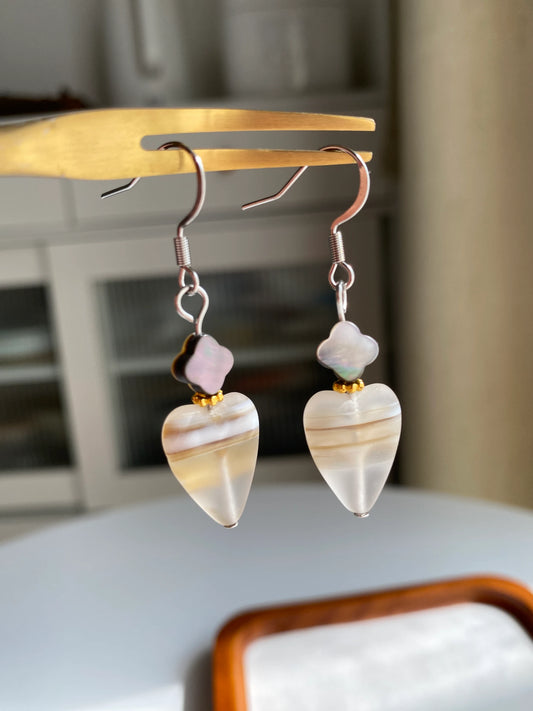 A 1-of-1 pair of minimalist retro earrings featuring frosted heart-shaped Czech glass and black clover shells on a fork.