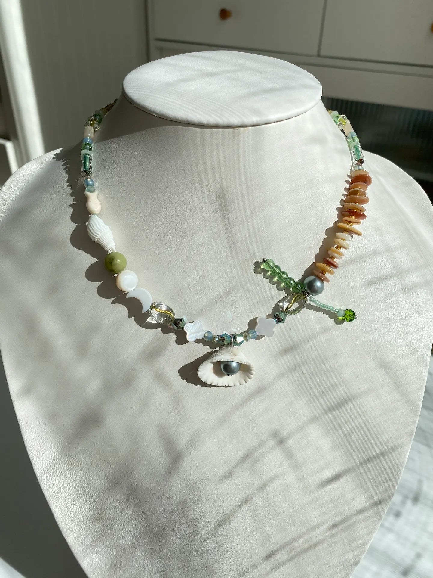 Close-up of the HuibenCraft 1-of-1 Pacific Breeze Shell and Czech Fish Necklace worn on a mannequin neck, showing perfect collarbone placement.