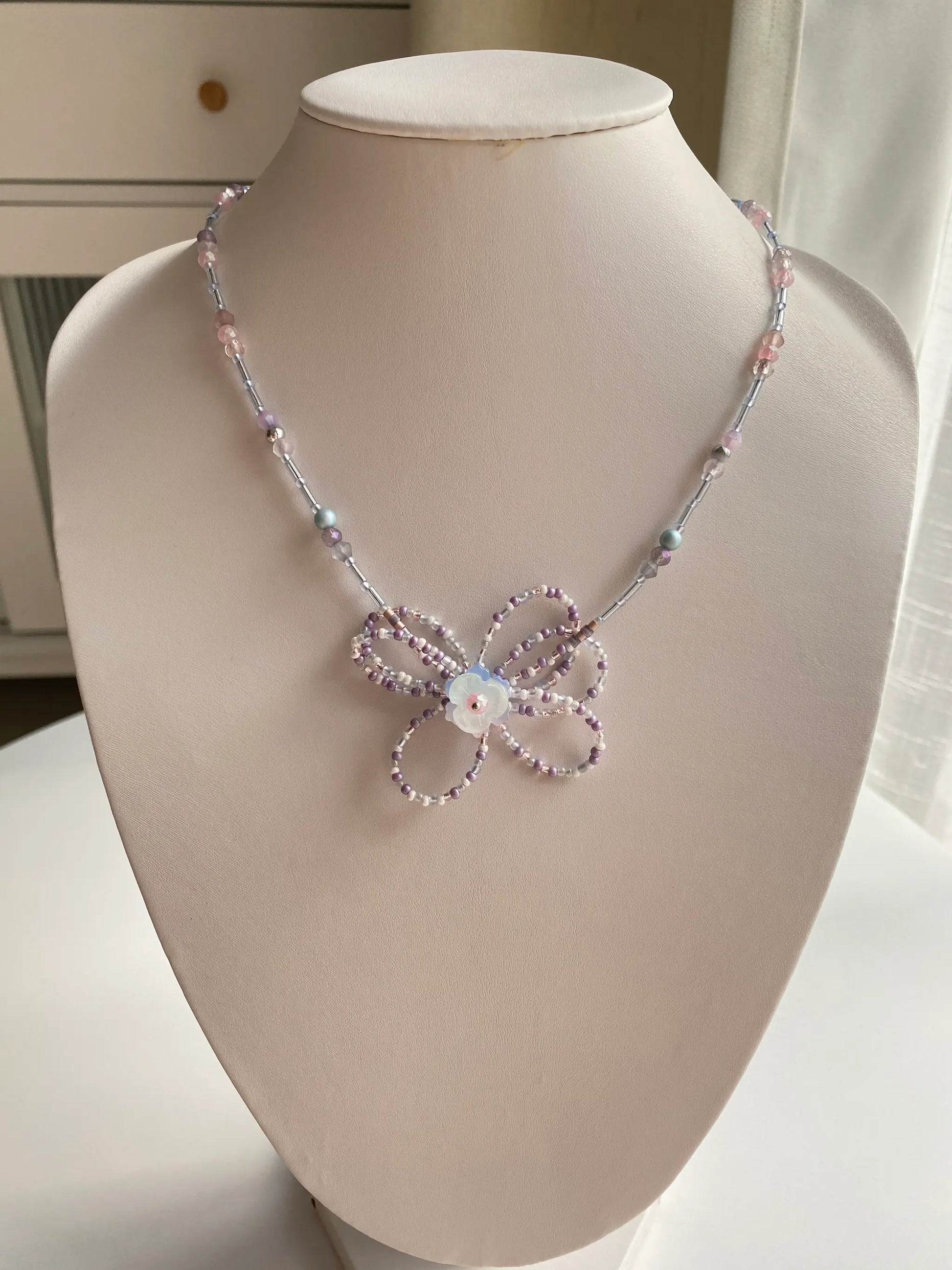 Handcrafted 1-of-1 long necklace with a woven floral pendant worn on a mannequin neck.