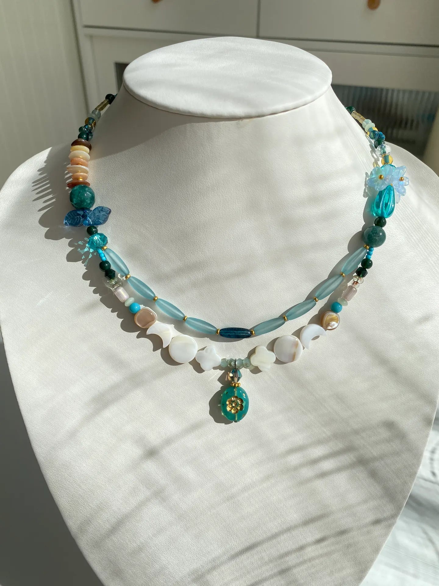 Handcrafted 1-of-1 heavy-duty layered necklace featuring a perfume bottle pendant and floral bead bouquets worn on a mannequin neck.