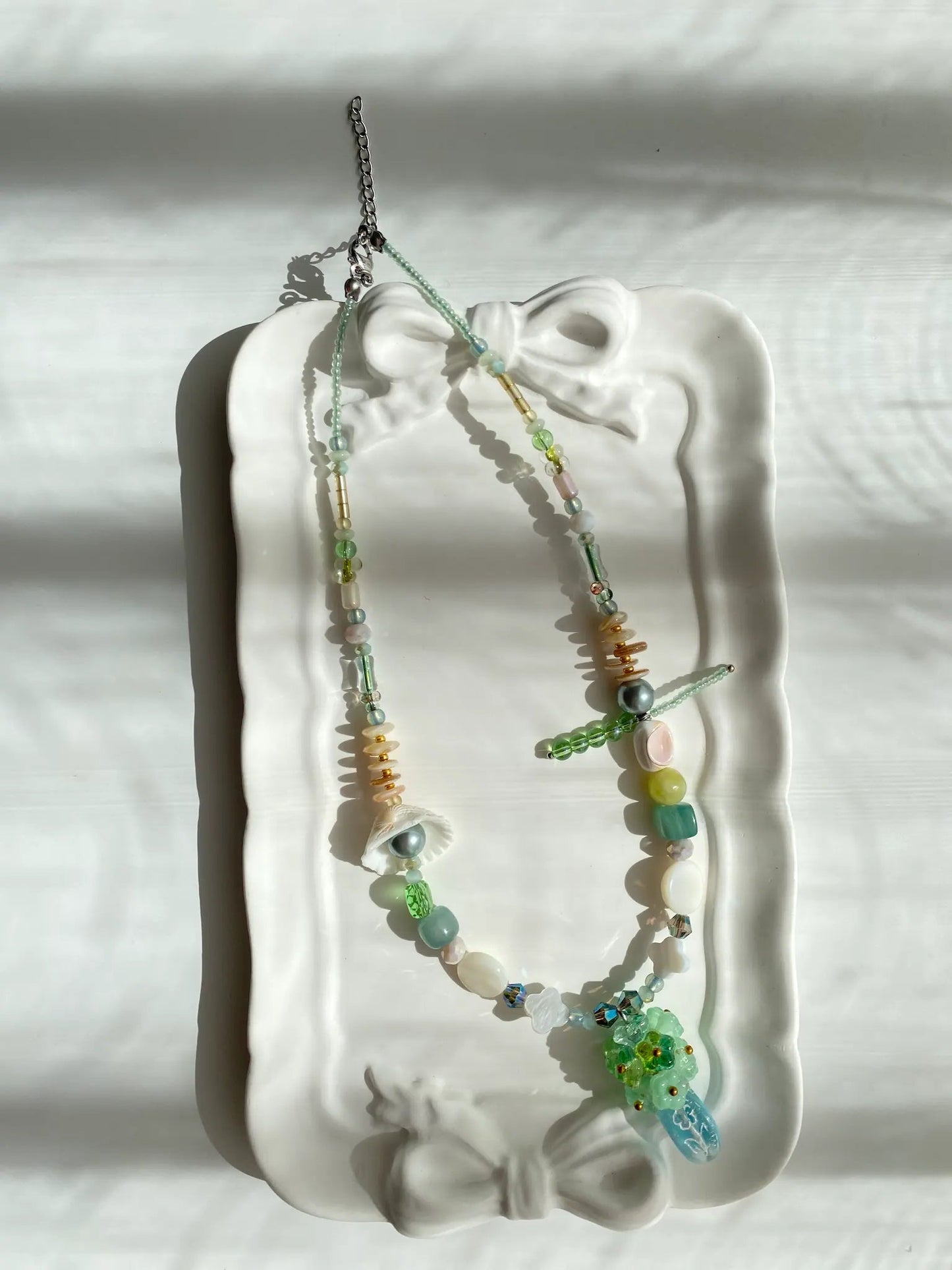 Poetic view of the 1-of-1 summer floral necklace resting on a ceramic plate, capturing a refreshing and gentle aesthetic.