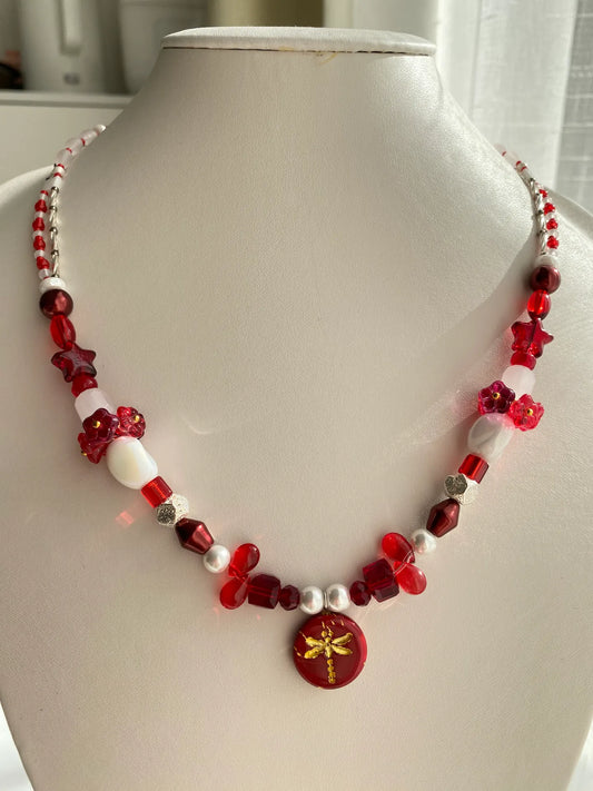 Handcrafted 1-of-1 ruby butterfly necklace featuring 3D floral glass vase accents worn on a mannequin neck.