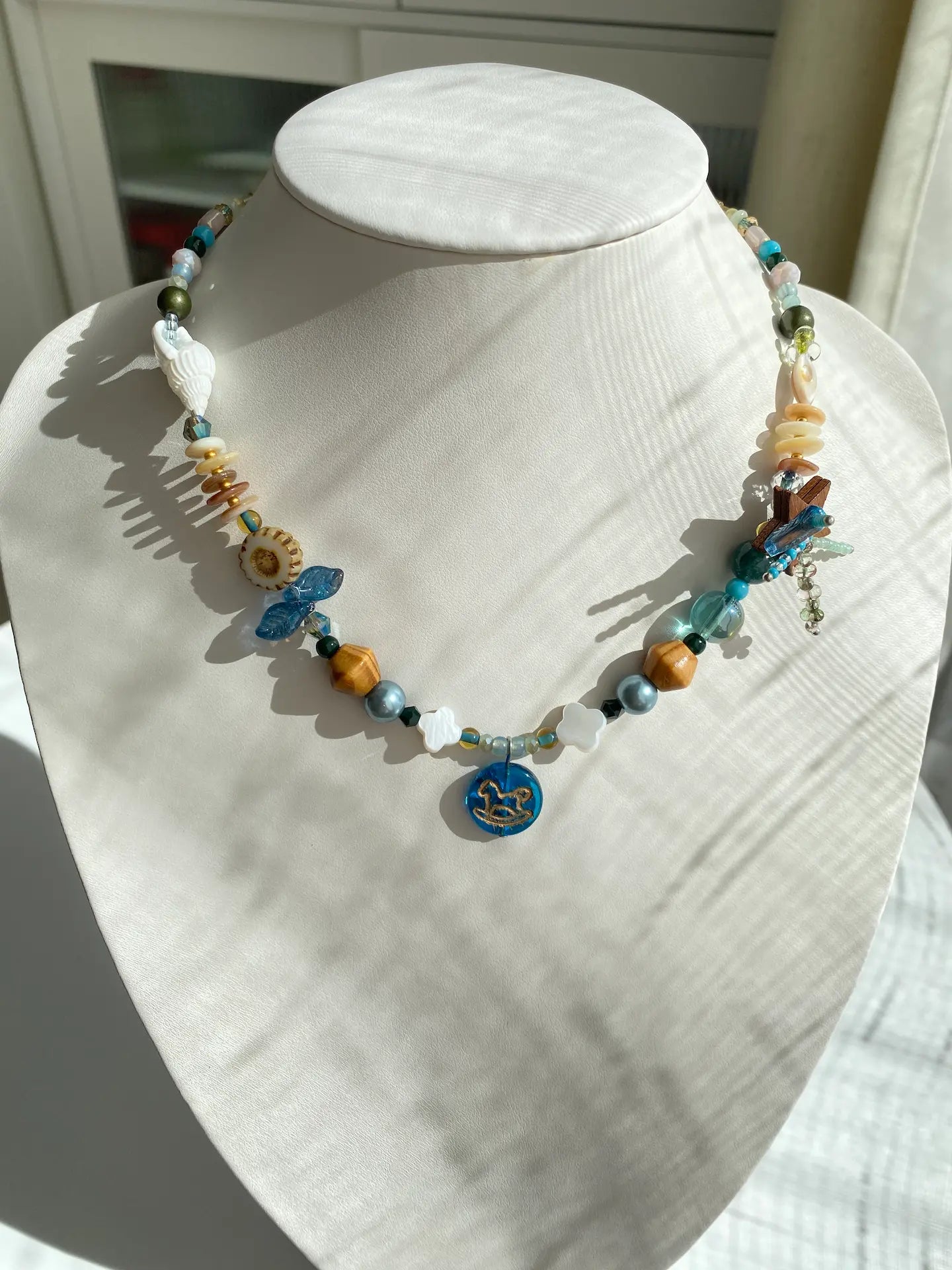 Close-up of the HuibenCraft 1-of-1 Starry Firework necklace with a blue Trojan horse pendant worn on a mannequin neck.