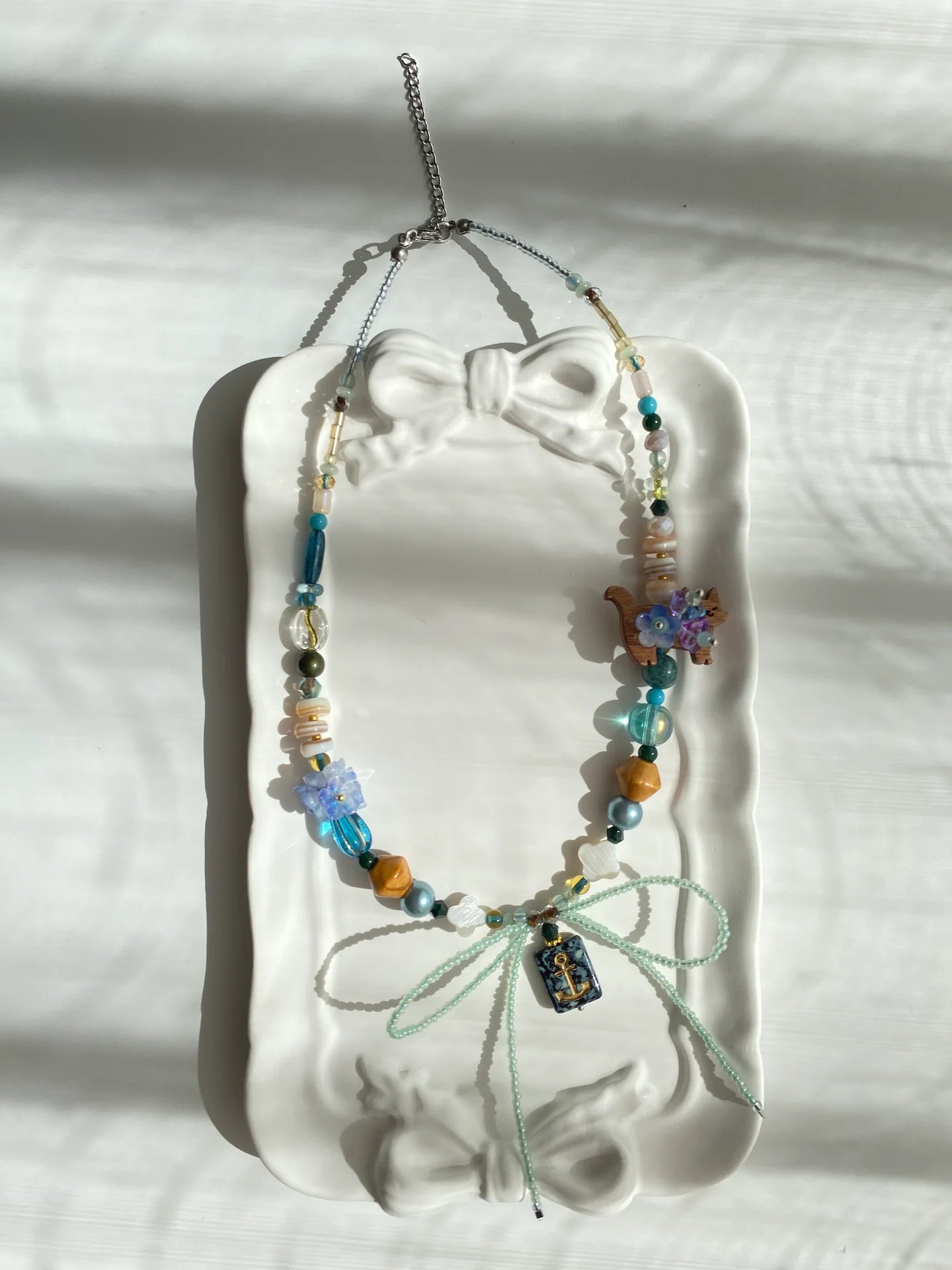 Poetic view of the 1-of-1 zodiac necklace resting on a ceramic plate, capturing a sweet and cool vacation aesthetic.