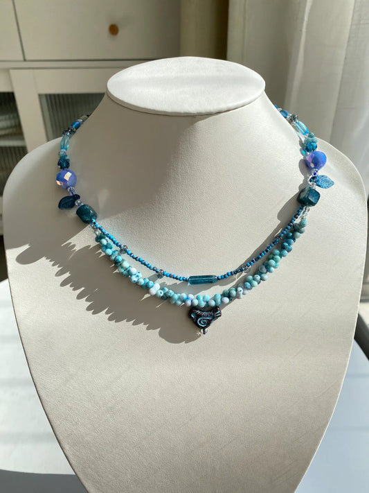 Handcrafted 1-of-1 double-layered necklace with a Czech glass chicken charm and natural blue stones worn on a mannequin neck.