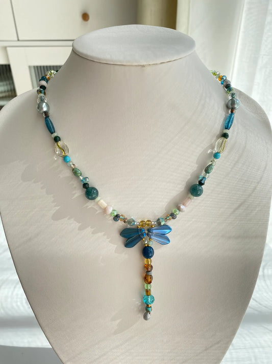 Handcrafted 1-of-1 blue dragonfly necklace featuring sword-shaped wing beads worn on a mannequin neck.