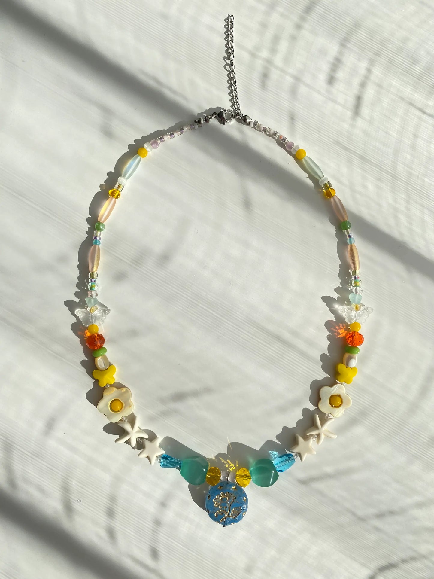 Gold-edged blue Margaret glass pendant shimmering brilliantly under direct natural sunlight on a flat surface.