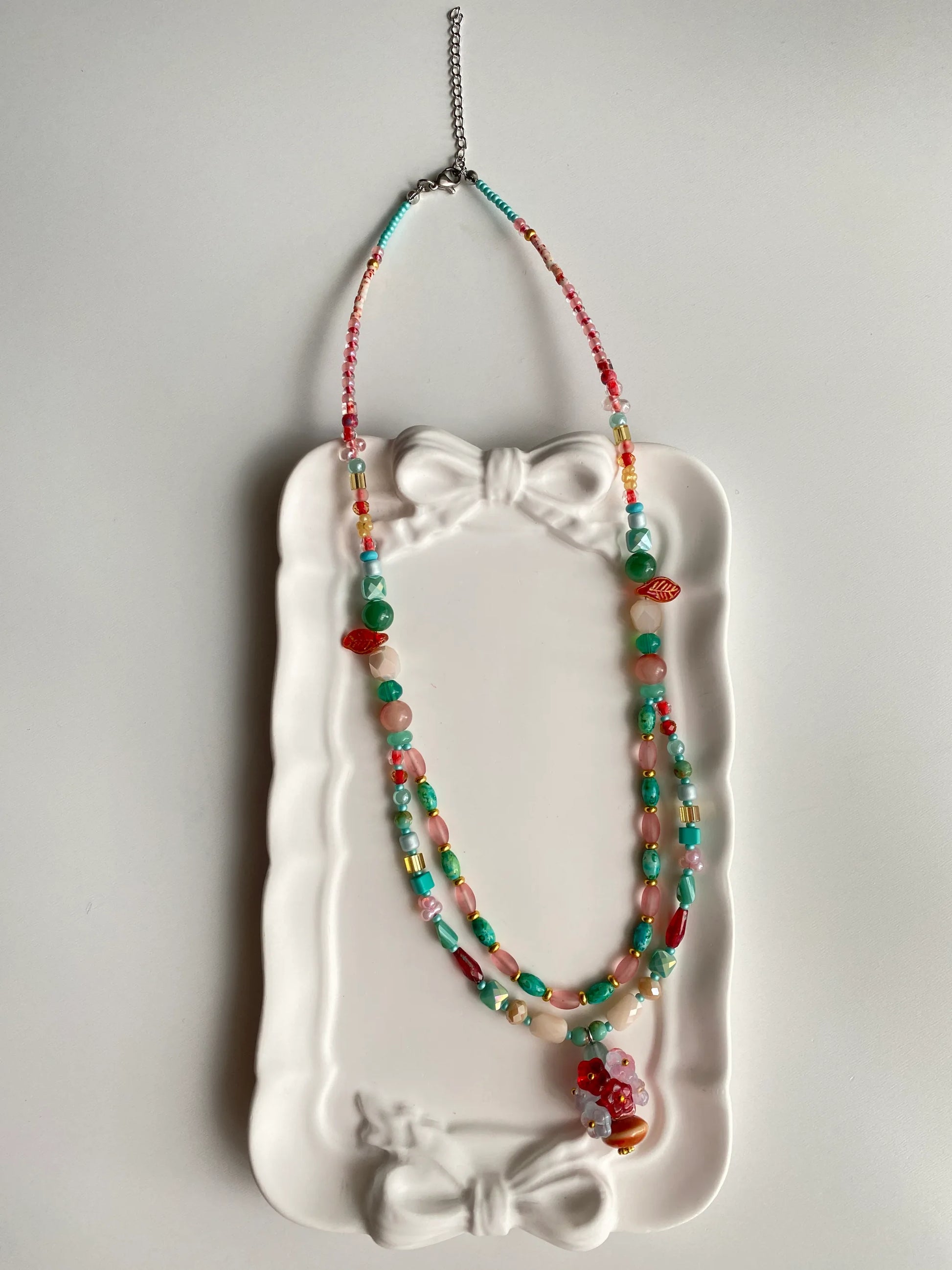 HuibenCraft 1-of-1 bold ethnic-inspired layered necklace with pine blue, red, and gold beads in a white ceramic dish.