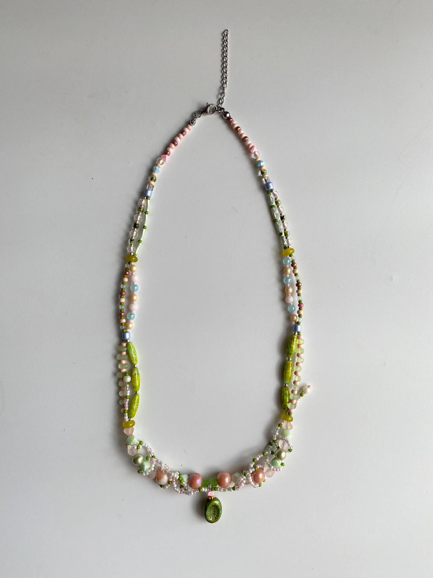 Flatlay of a handmade heavy-beaded necklace featuring vine-like beadwork on a white table.