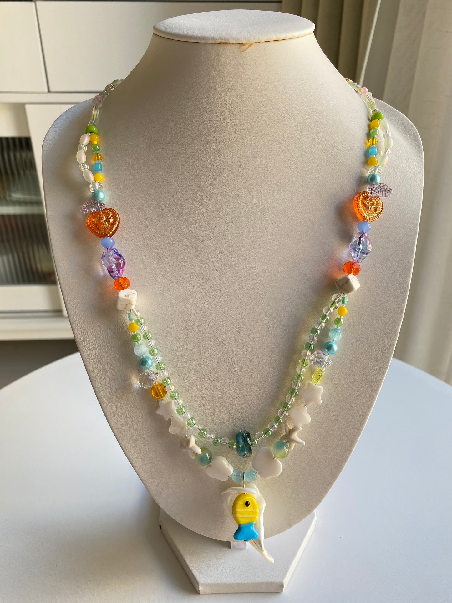 Long handmade ocean necklace featuring shell pendant and colorful fish charms.