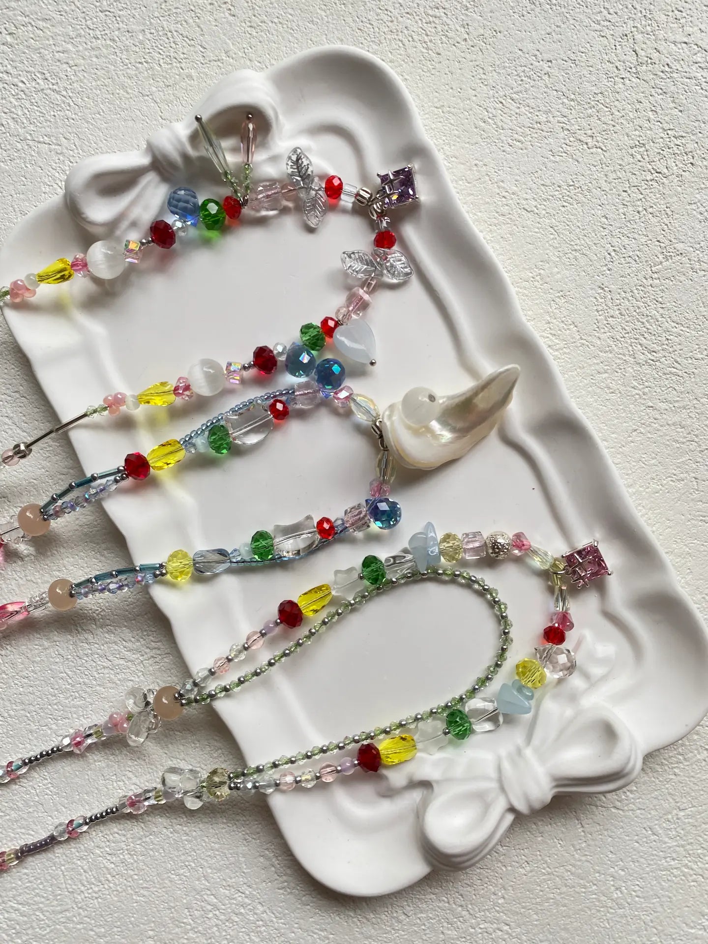 Close-up top-down view of HuibenCraft handmade colorful chokers showcasing intricate seed bead details, shell, and lampwork glass pendants.