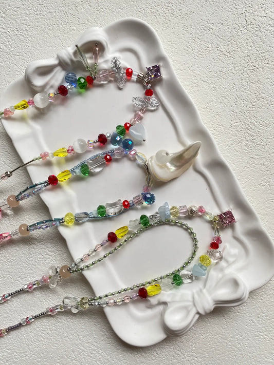 Close-up top-down view of HuibenCraft handmade colorful chokers showcasing intricate seed bead details, shell, and lampwork glass pendants.