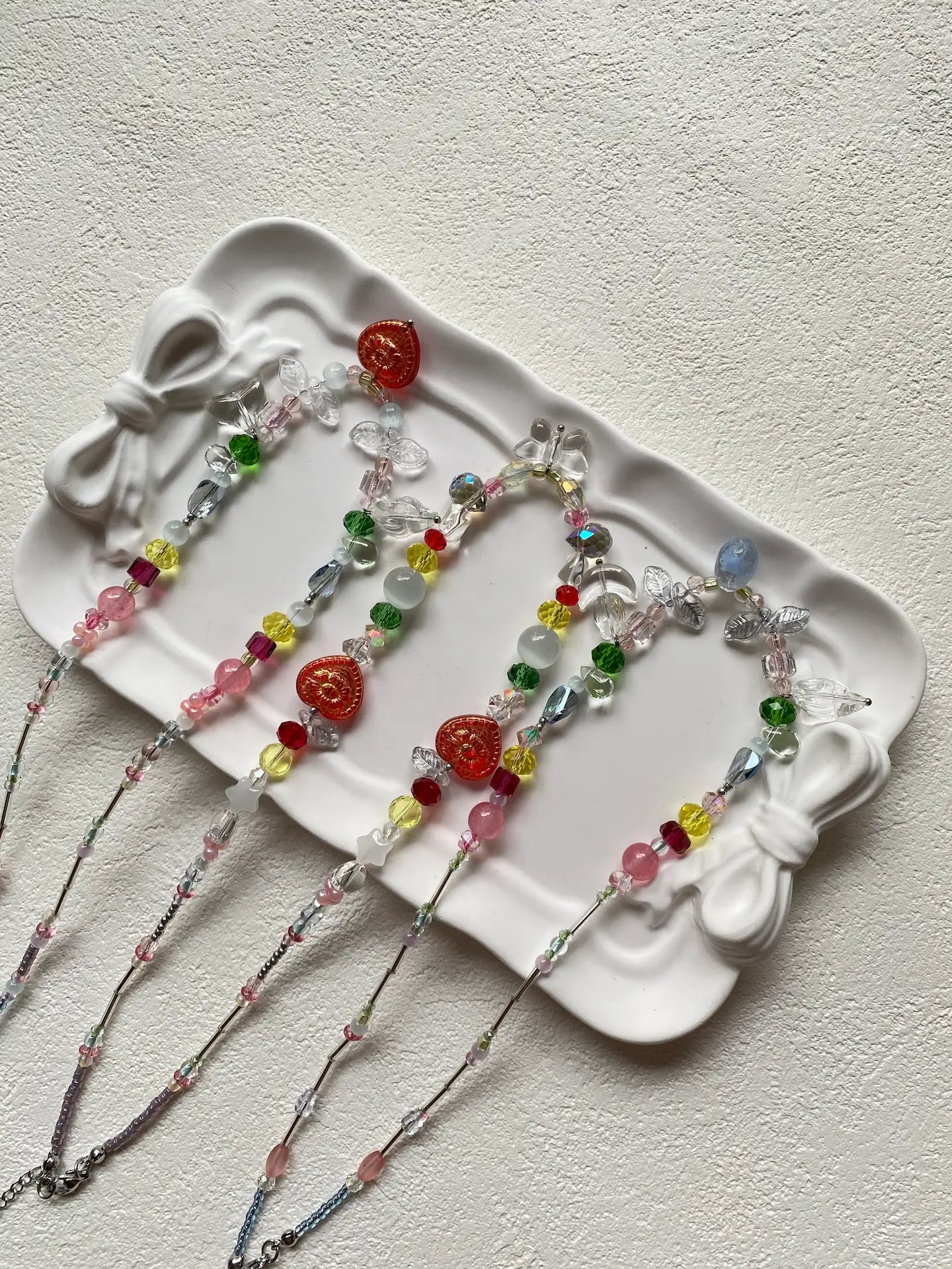 Detailed top-down shot of three dazzling HuibenCraft mixed-color seed bead necklaces glittering together, featuring floral, shell, and lampwork glass accents.