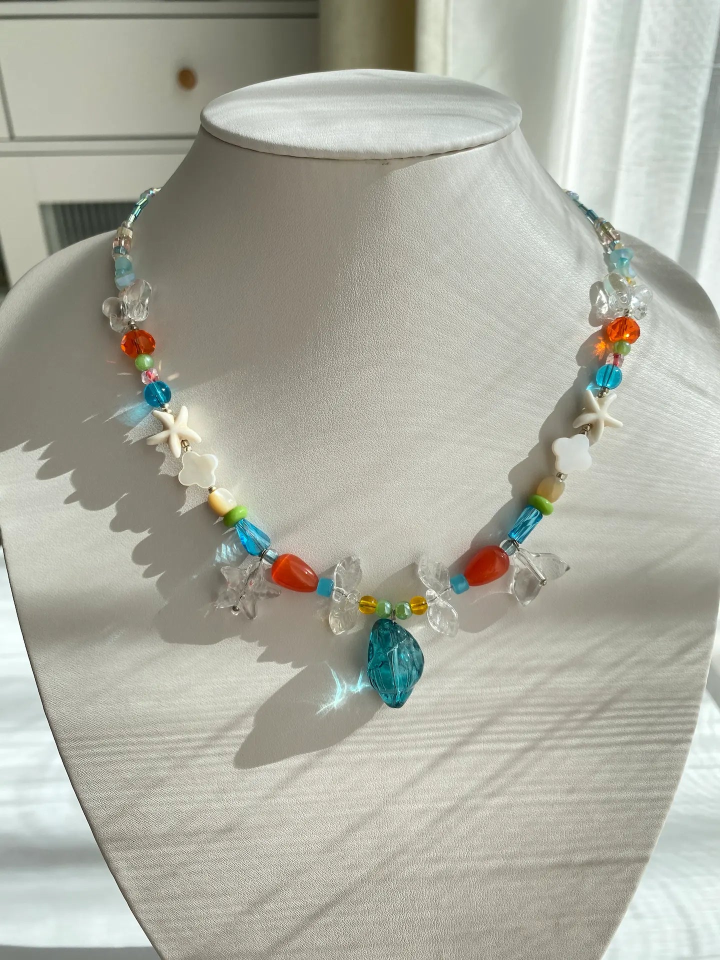 The mystic sea conch and fish tail necklace displayed on a mannequin, perfect for a coastal chic outfit.