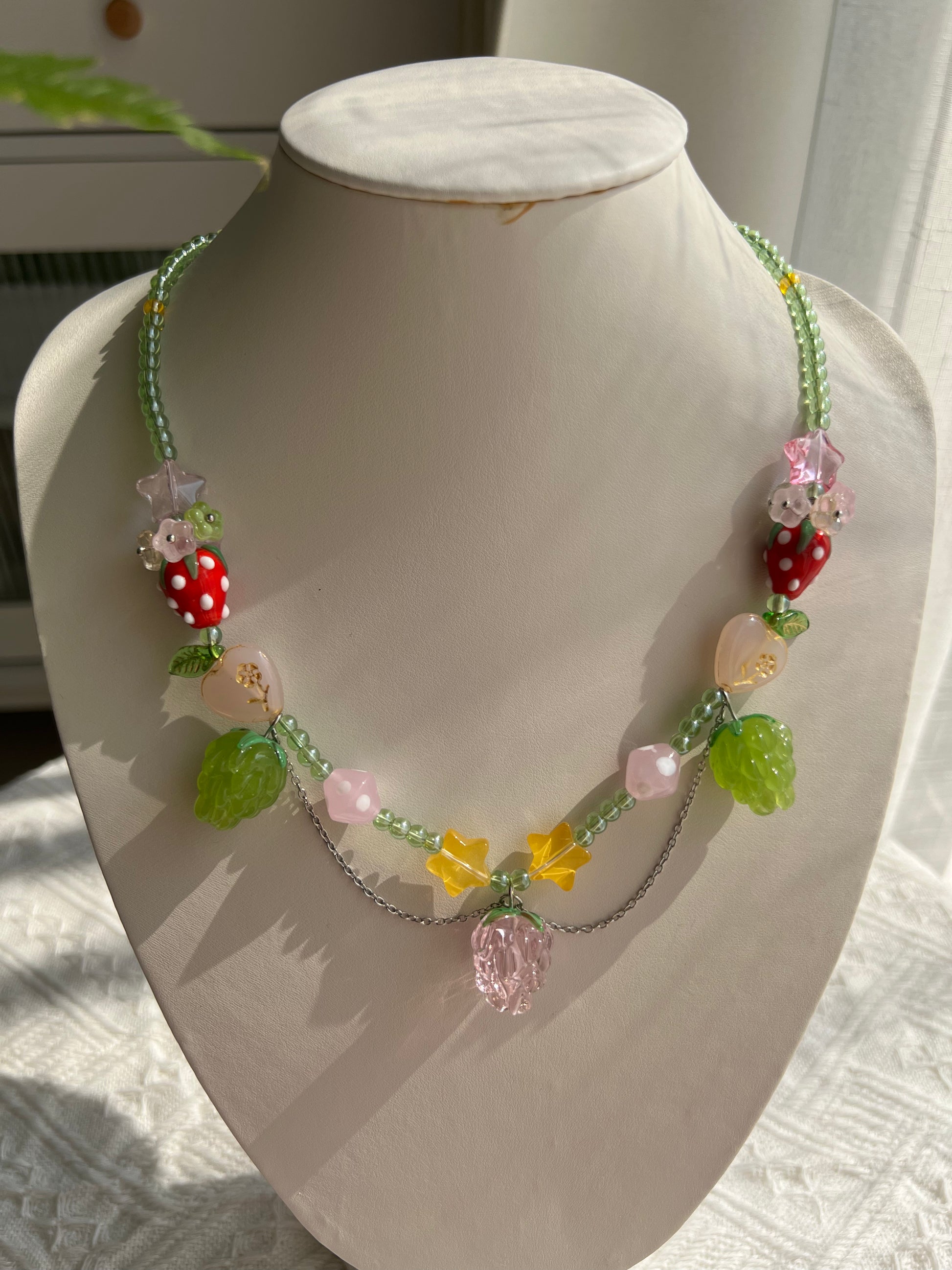 Cute Raspberry Strawberry Necklace displayed on a necklace bust with colorful fruit beads.