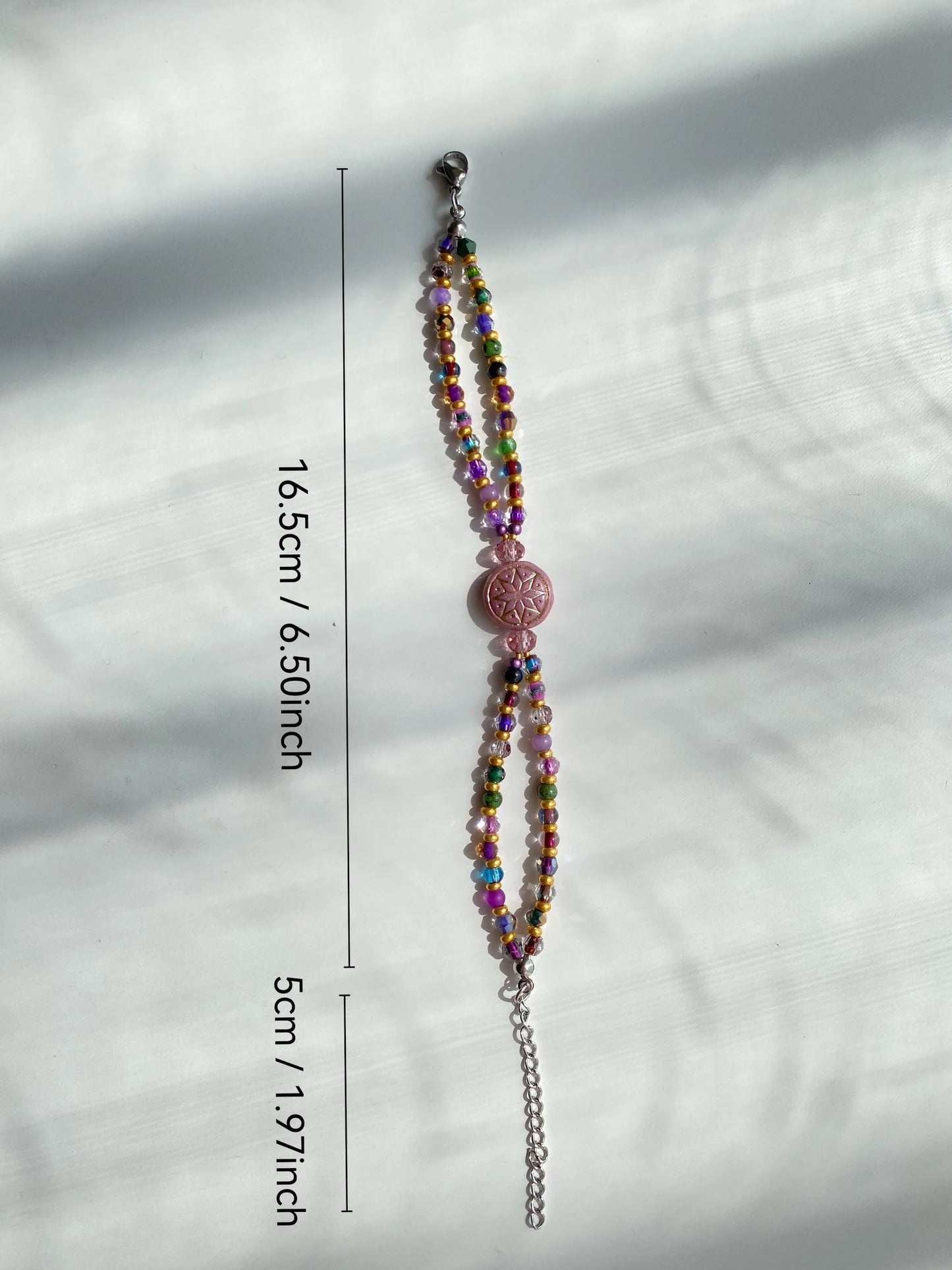 A close-up of a 1-of-1 deep purple Octagram double-layered bracelet on a white desk with soft sun shadows.