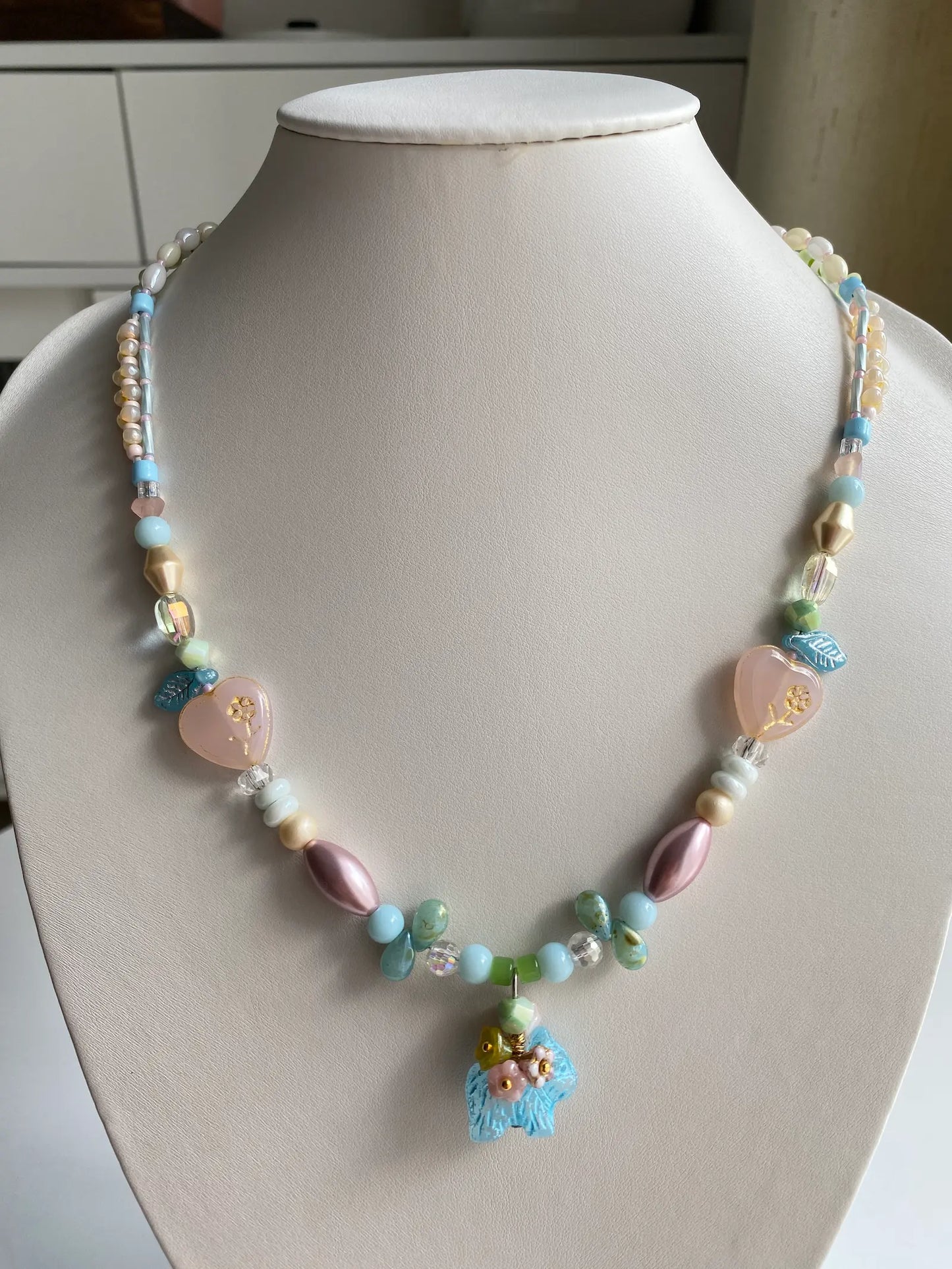 A HuibenCraft 1-of-1 beaded necklace with a flower-back dog pendant on a mannequin.