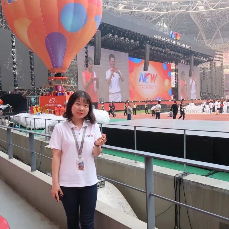 HuibenCraft founder wearing an Alibaba staff ID and event T-shirt at the 20th-anniversary stadium ceremony in Hangzhou, representing 12 years of corporate operations expertise.