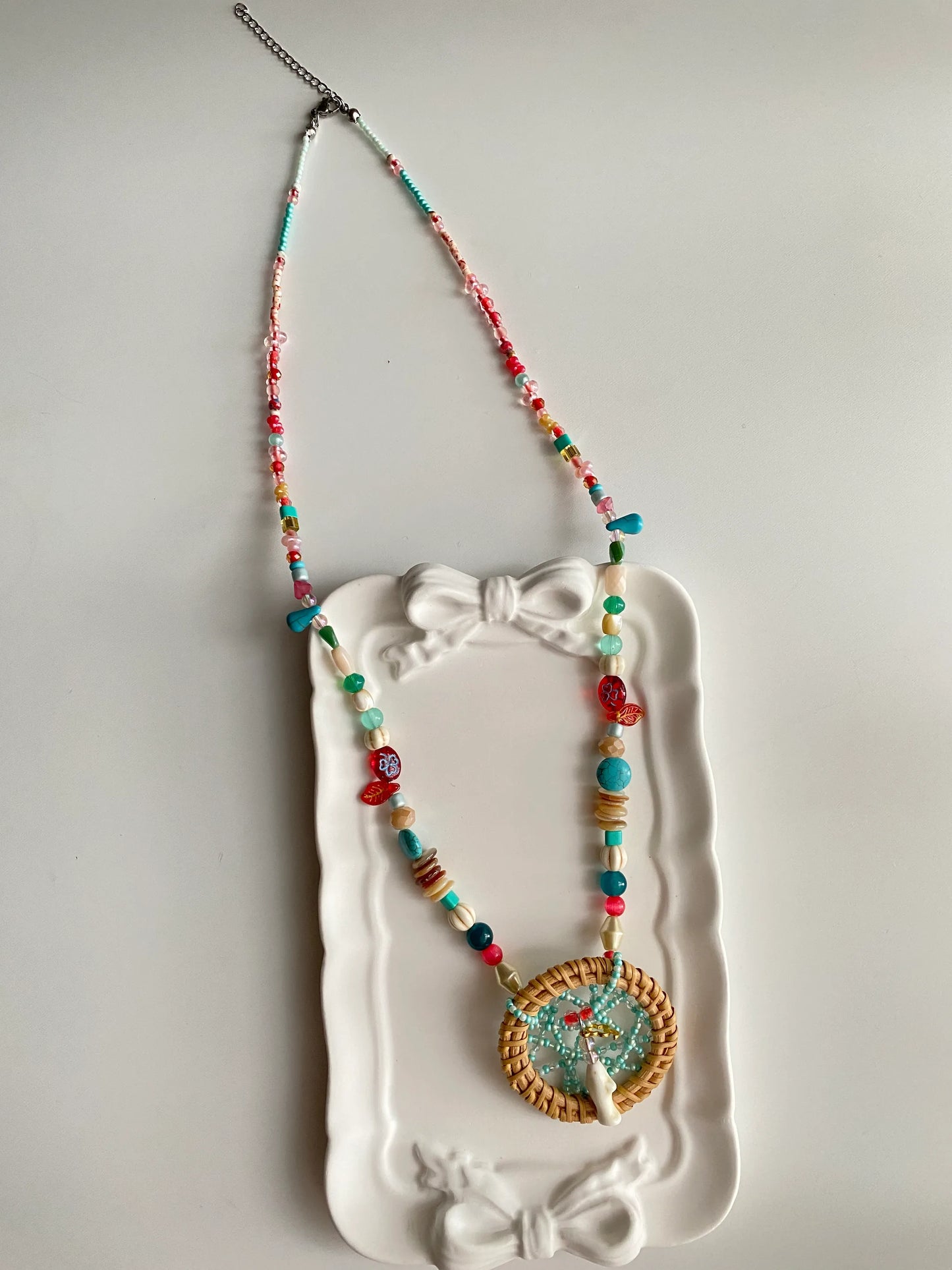 HuibenCraft 1-of-1 heavy-workmanship dreamcatcher necklace with white pine stone accents in a white ceramic dish, a unique artisan gift.