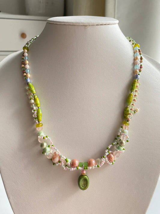 A HuibenCraft 1-of-1 heavy-beaded botanical necklace with a kiwi pendant on a mannequin.