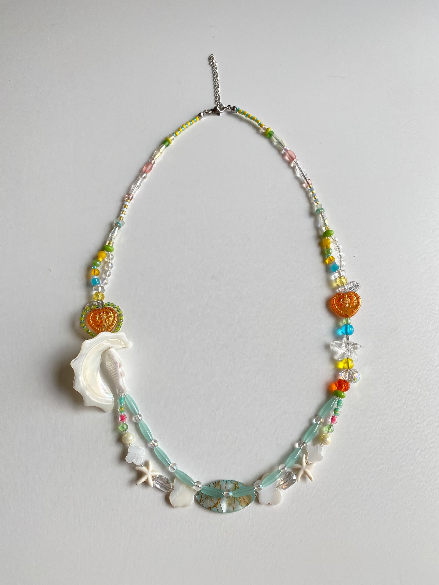 Close-up of fish charm, shell pendant and colorful beadwork.