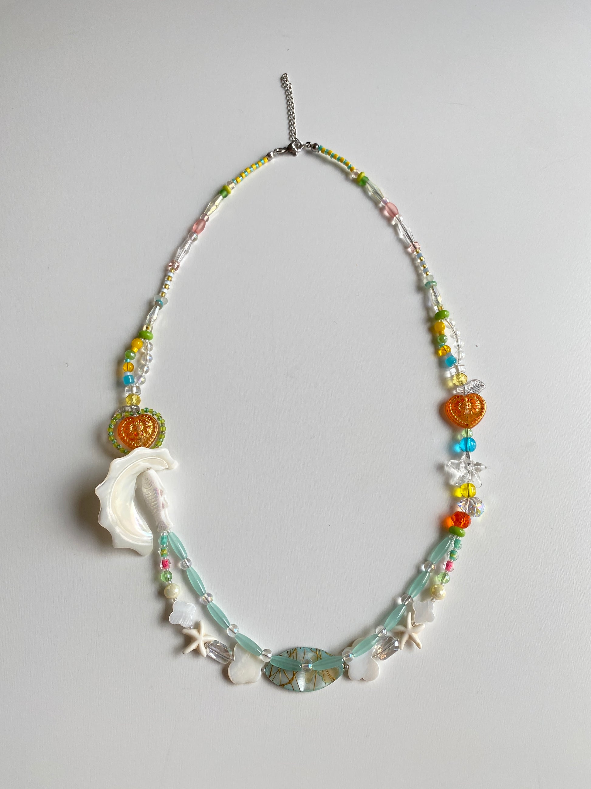 Close-up of fish charm, shell pendant and colorful beadwork.