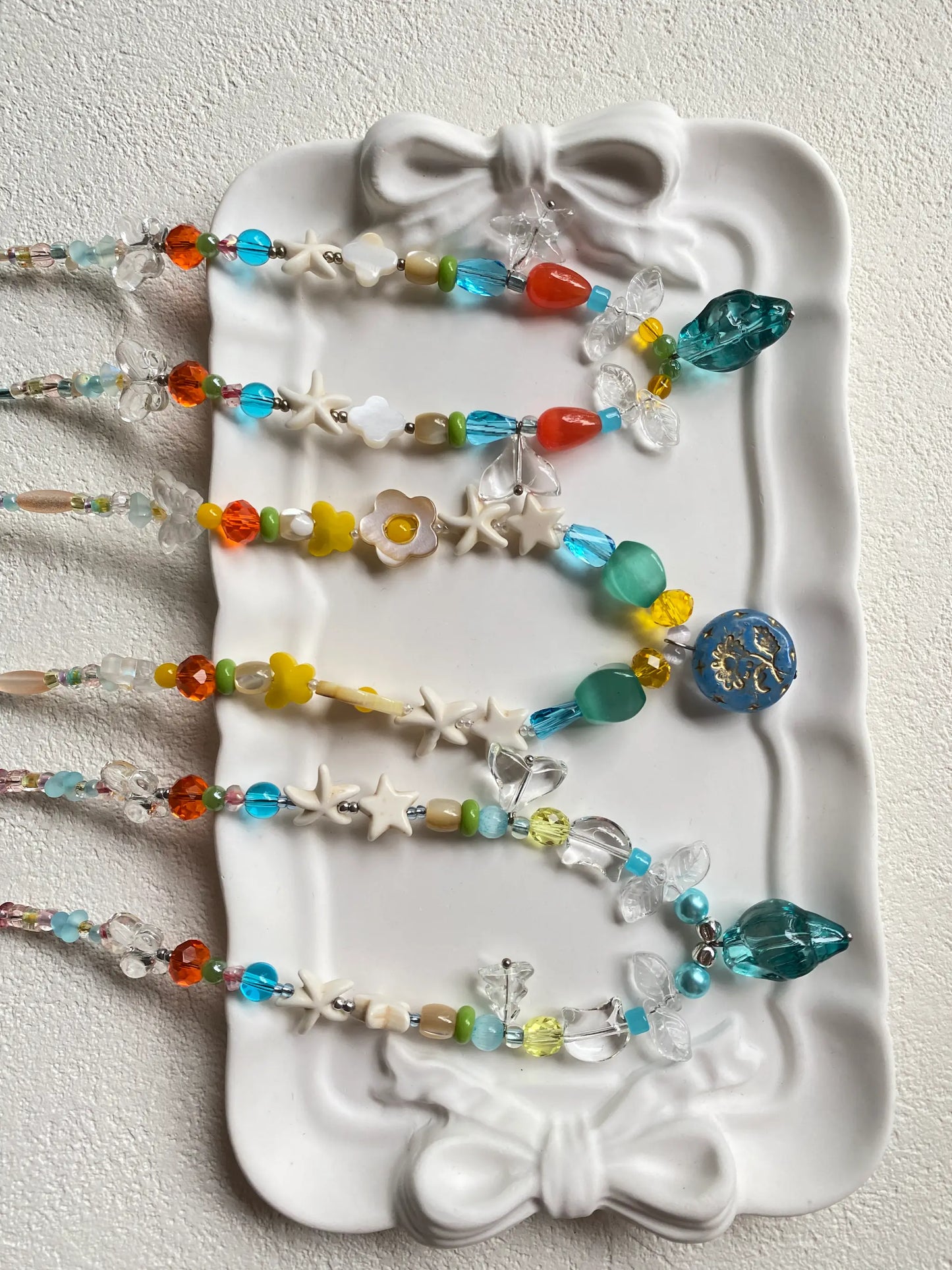 Close-up of handcrafted jewelry details showing translucent glass beads, starfish charms, and white turquoise stars in the sun.