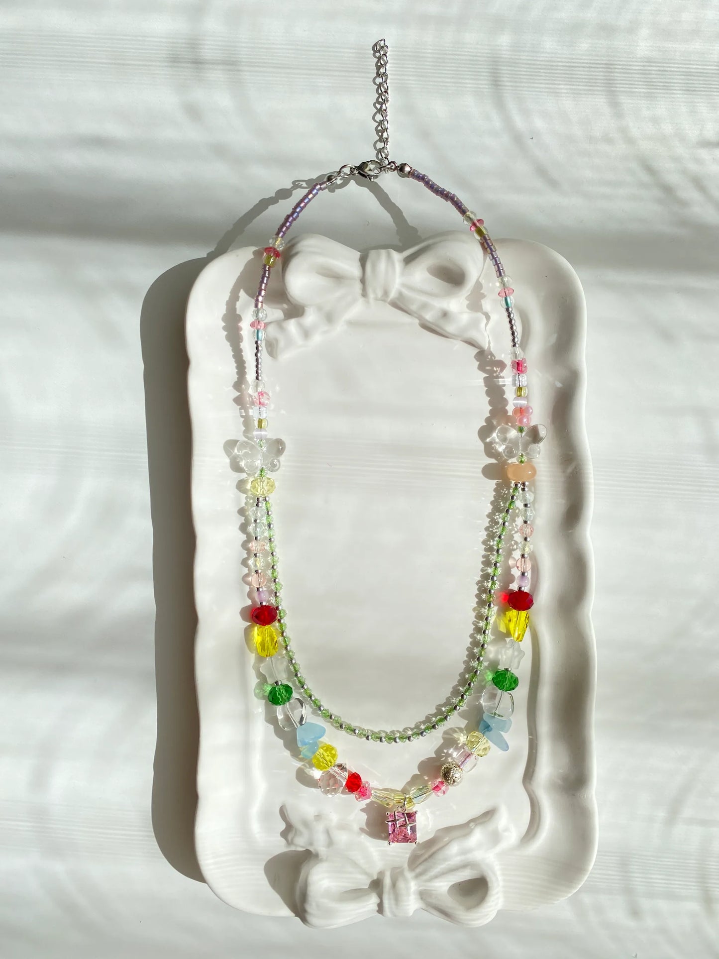 HuibenCraft 1-of-1 colorful beaded choker with a brilliant pink lampwork glass pendant, resting elegantly inside a dish under natural light.