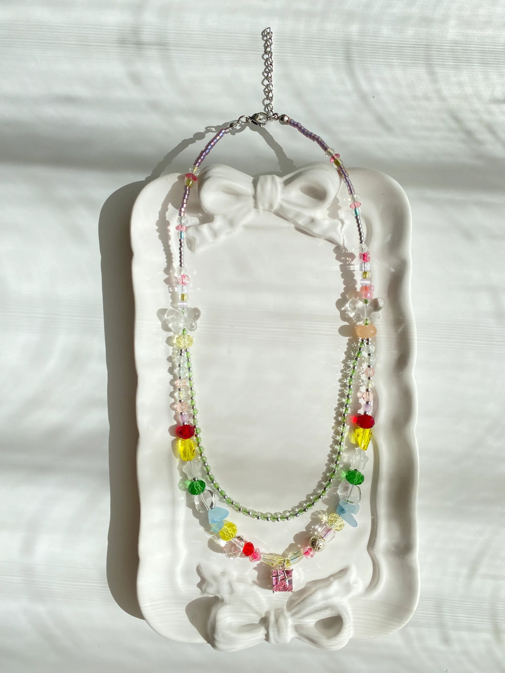HuibenCraft 1-of-1 colorful beaded choker with a brilliant pink lampwork glass pendant, resting elegantly inside a dish under natural light.
