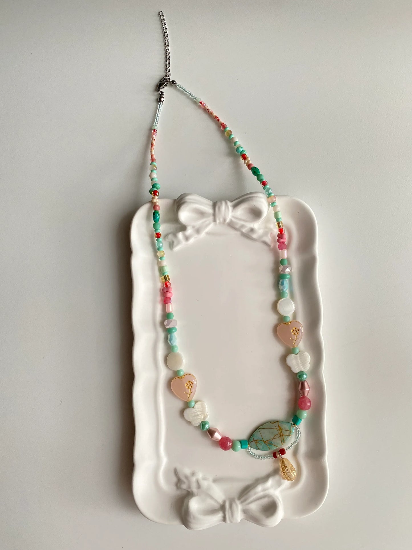HuibenCraft 1-of-1 playful ethnic-style necklace with vibrant beads and unique shell textures in a white ceramic dish under natural light.