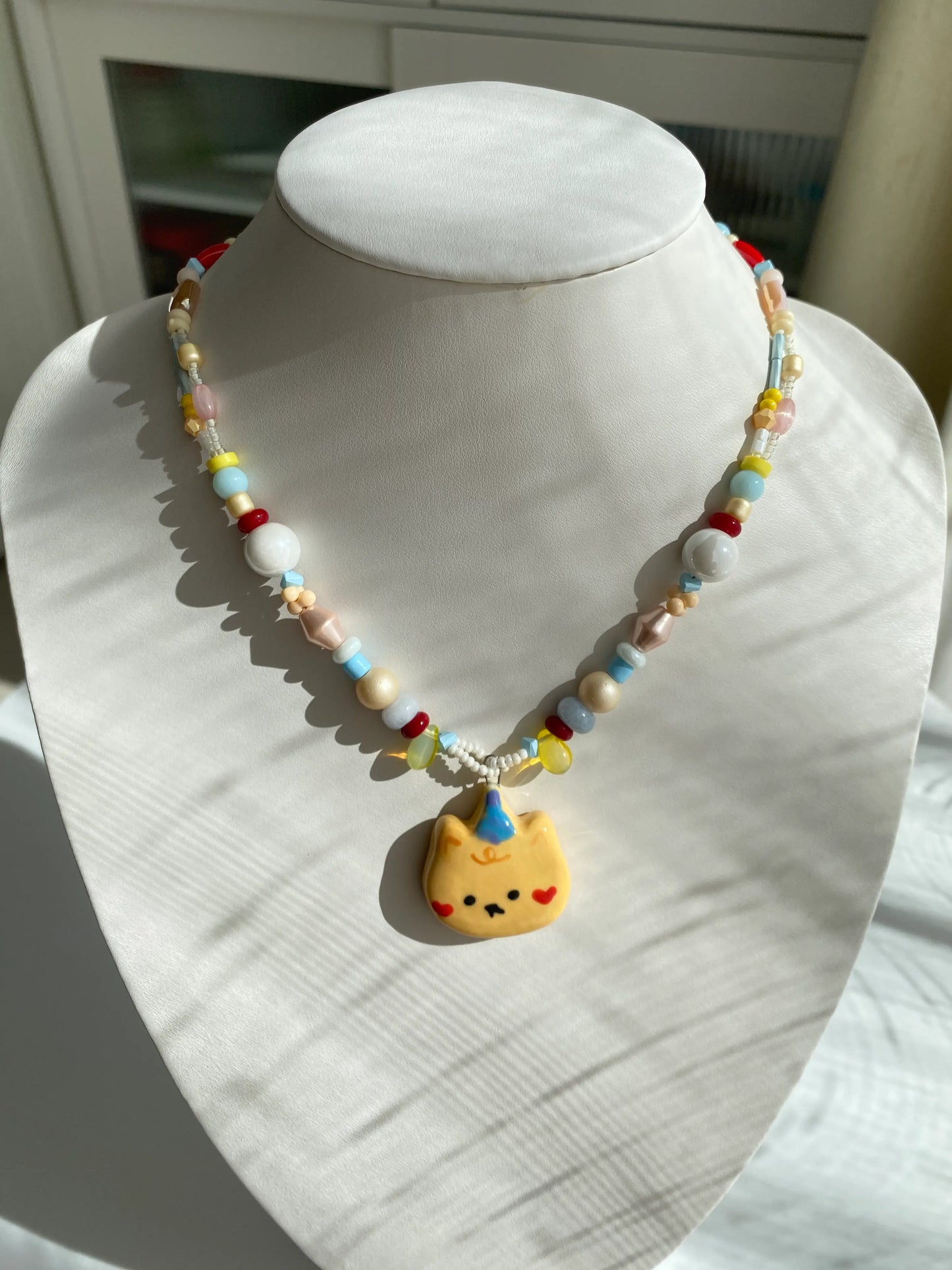 HuibenCraft 1-of-1 beaded necklace with a yellow ceramic bear charm on a mannequin.