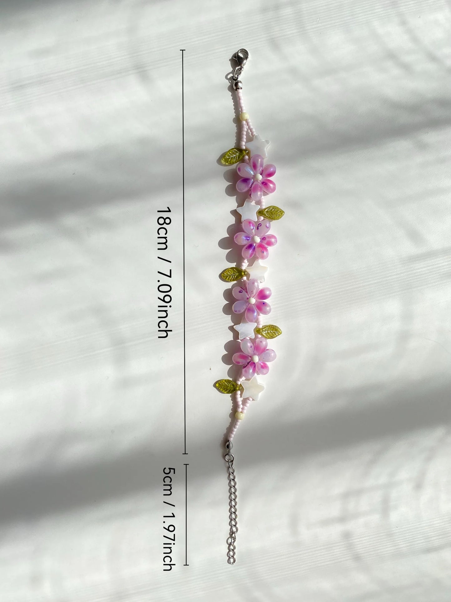 Handcrafted 1-of-1 purple waterdrop floral bracelet with a star shell charm, double-layered look on a white surface with natural light.
