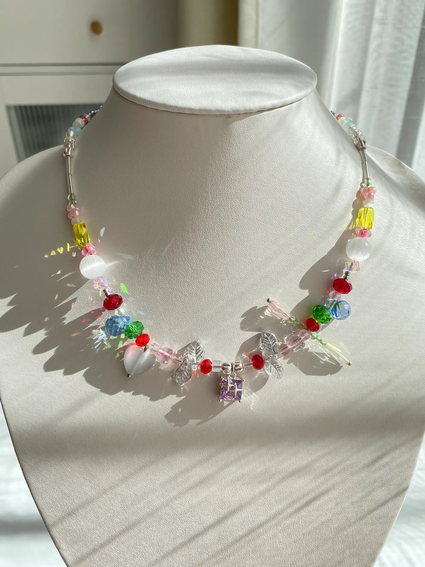 HuibenCraft vibrant rainbow-style seed bead necklace with a shiny purple lampwork glass pendant worn on a jewelry mannequin neck.