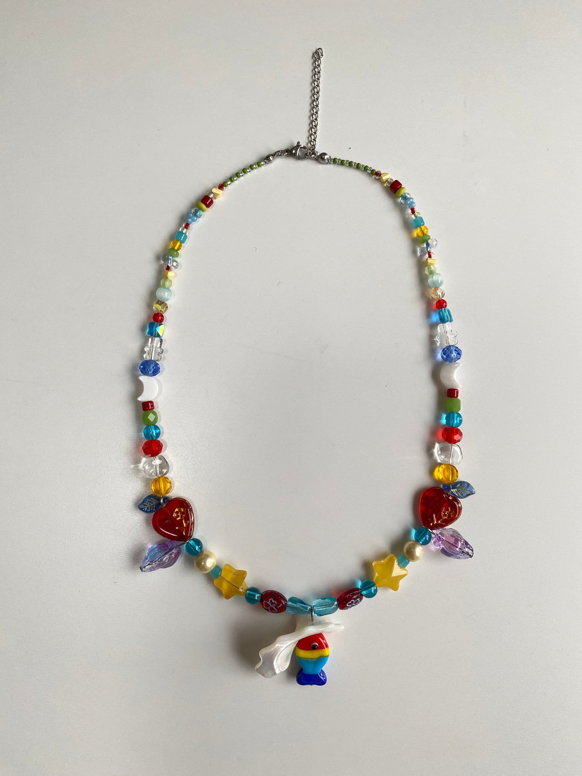 Handmade beach necklace displayed on a necklace bust with a colorful Czech glass fish, shell pendant and playful seaside-inspired beadwork.
