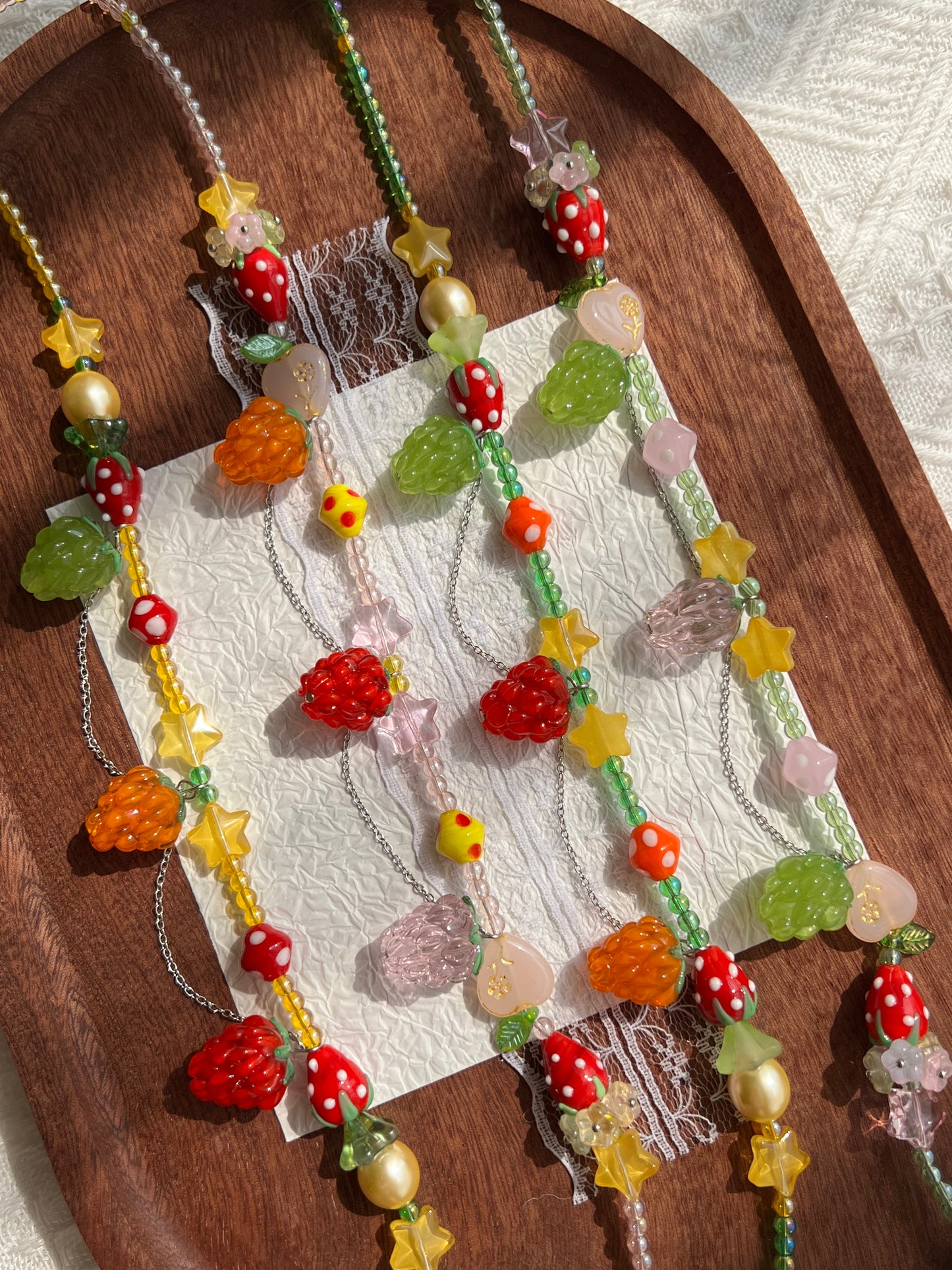 Close-up of the raspberry pendants and strawberry glass beads on the necklace collection.