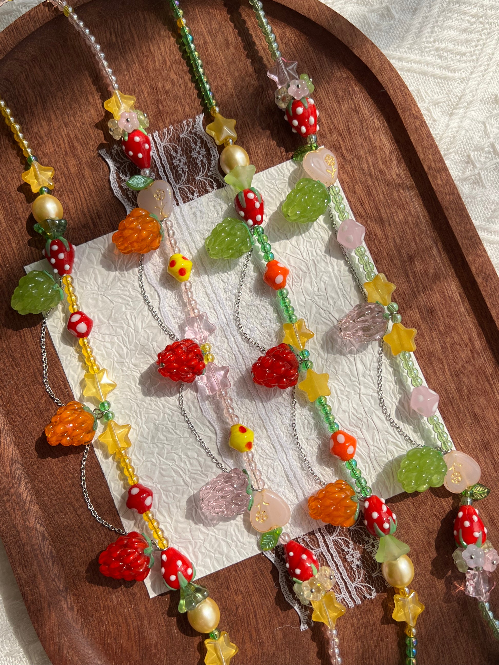 Close-up of the raspberry pendants and strawberry glass beads on the necklace collection.